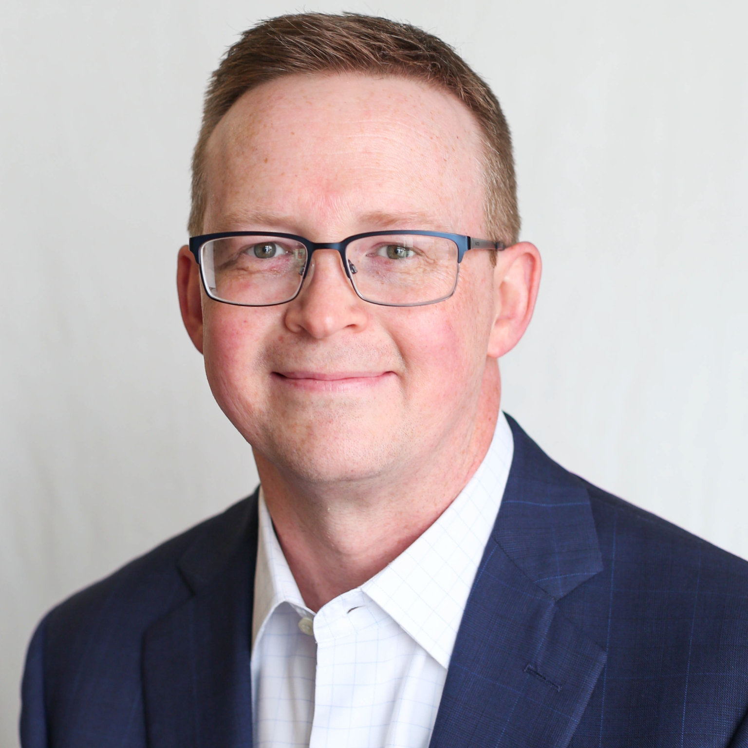 A headshot of a man in a blue suit jacket.